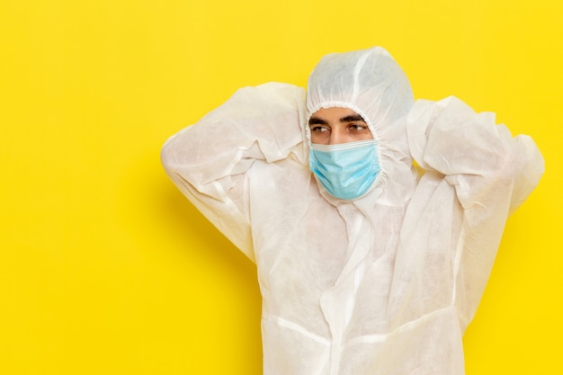 Foto gratuita vista frontale del lavoratore scientifico maschio in tuta protettiva speciale e con maschera stanca sul muro giallo chiaro