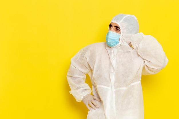 특수 보호 흰색 양복과 노란색 벽에 마스크 생각 남성 과학 노동자의 전면보기