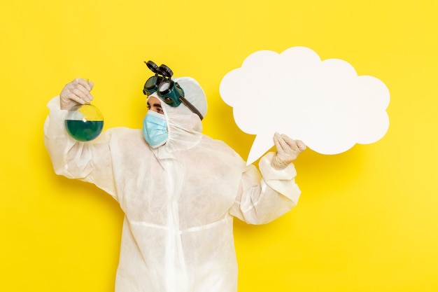 Free photo front view male scientific worker in special suit holding flask with green solution and big white sign on the yellow desk