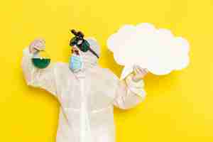 Free photo front view male scientific worker in special suit holding flask with green solution and big white sign on the yellow desk