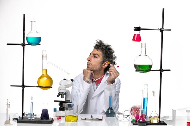 Front view male scientist holding samples in front of table with solutions on the white background coronavirus health lab covid