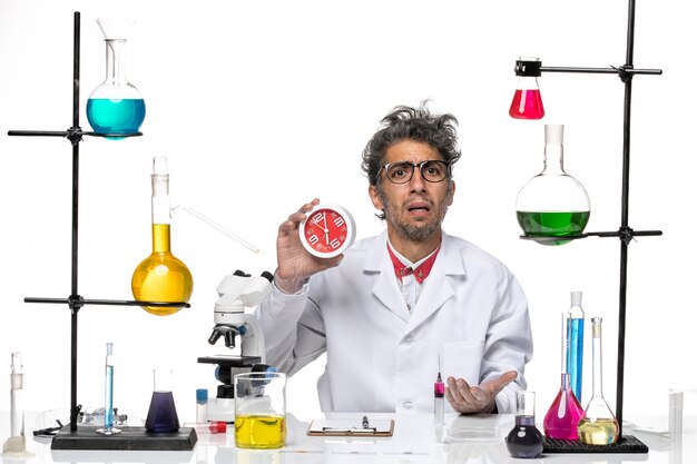 Вид спереди ученый-мужчина в медицинском костюме, держа часы на белом фоне, химия, лаборатория вируса covid, здоровье