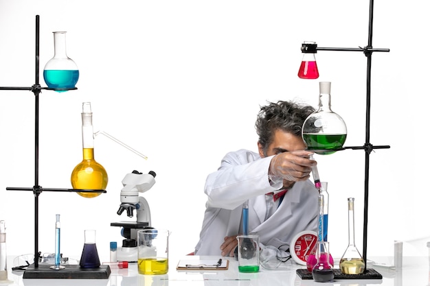 Front view male scientist in medical suit holding flask with solution on light-white background lab coronavirus health covid