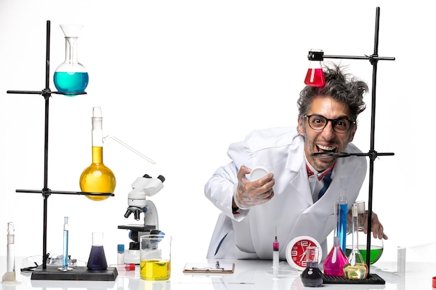 Front view male scientist in medical suit working with different solutions and laughing on white background chemistry covid lab virus