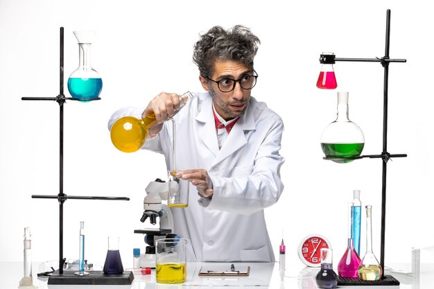 Вид спереди ученый-мужчина в медицинском костюме, работающий с различными растворами на светлом белом фоне, вирусная химия здоровья лаборатории covid