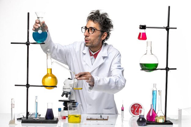 Вид спереди ученый-мужчина в медицинском костюме, работающий с различными растворами на белом фоне, химия здоровья вируса лаборатории covid