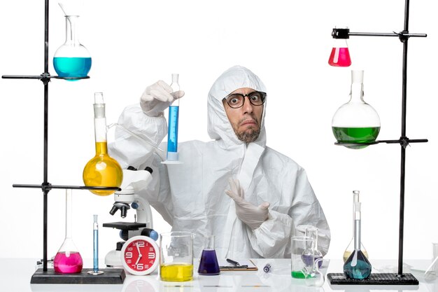 Вид спереди ученый-мужчина в специальном защитном костюме, держащий фляжку с синим раствором