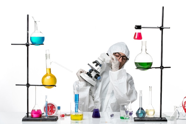 Вид спереди ученый-мужчина в специальном защитном костюме с микроскопом