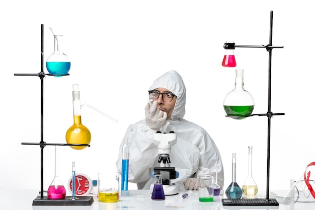 Free photo front view male scientist in special protective suit sitting with different solutions