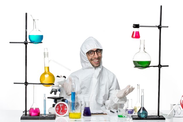 Вид спереди ученый-мужчина в специальном защитном костюме, сидящий с решениями, улыбаясь