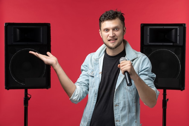 Foto gratuita vista frontale del cantante maschio che si esibisce sul palco sul muro rosso