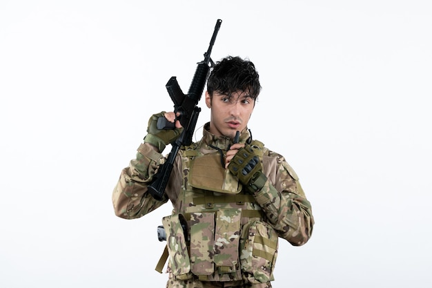 Free photo front view of male soldier in camouflage with machine gun white wall