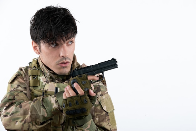 Foto gratuita soldato maschio di vista frontale che combatte durante il funzionamento con la parete bianca della pistola