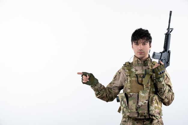 Front view male soldier with machine gun in camouflage white wall