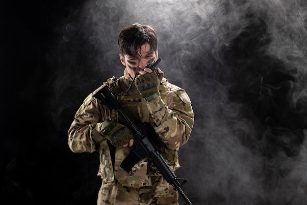 Вид спереди мужчины-солдата с пулеметом, использующего черную стену рации