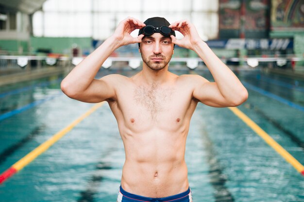 Front view male swimmer putting on swimming goggles