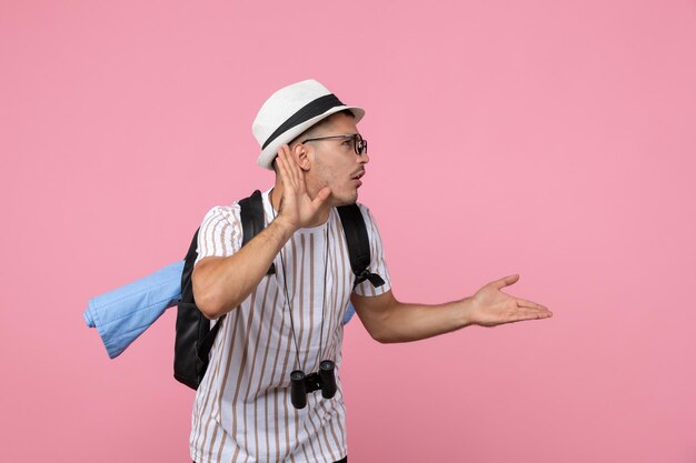 Front view male tourist listening closely on pink wall emotion tourist color