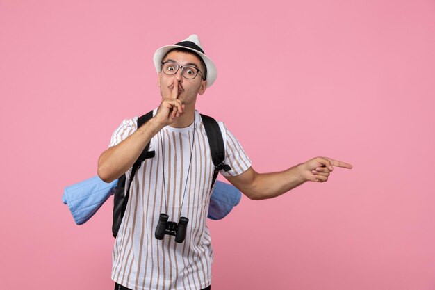 Вид спереди мужской турист позирует с рюкзаком на розовой стене эмоции туристического цвета