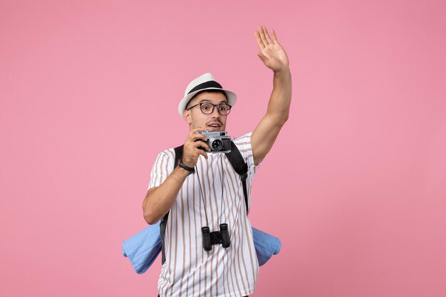 Front view male tourist taking photos with camera on pink wall emotion color tourist