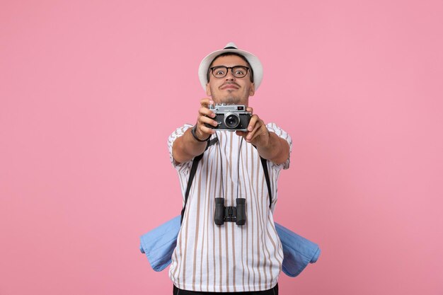 분홍색 벽 감정 관광 색상에 카메라와 함께 사진을 찍는 전면보기 남성 관광객