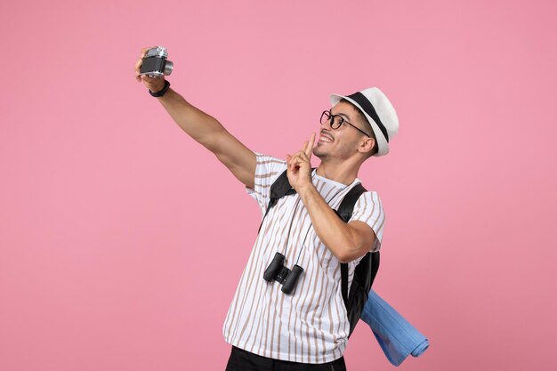 Front view male tourist taking photos with camera on pink wall emotion tourist color