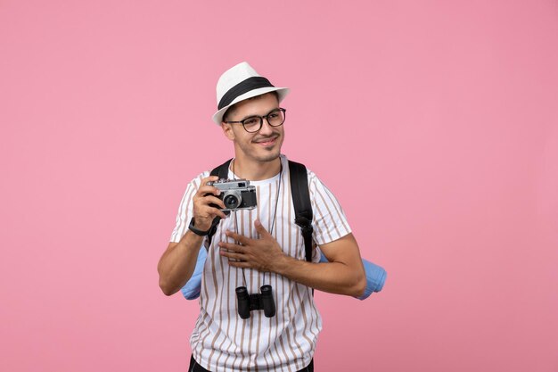 Вид спереди мужской турист с камерой на розовой стене эмоции цветной турист