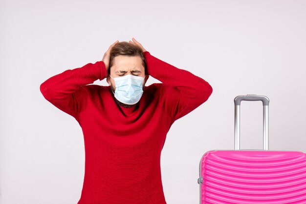 Foto gratuita turista maschio vista frontale con borsa rosa in maschera stressata sul muro bianco