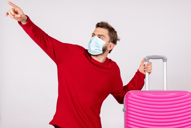 Front view male tourist with pink bag in mask on white wall