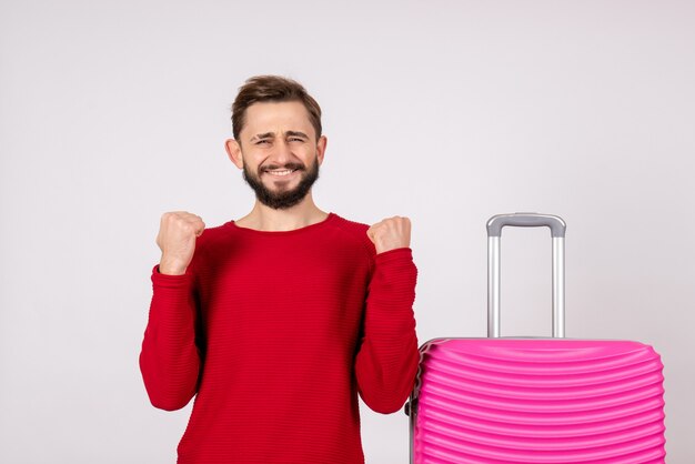 Front view male tourist with pink bag rejoicing on white wall