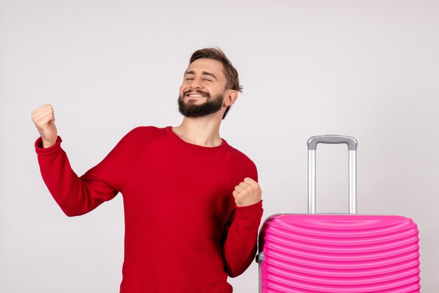 Front view male tourist with pink bag rejoicing on white wall