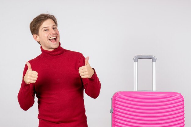 Front view of male tourist with pink bag on the white wall