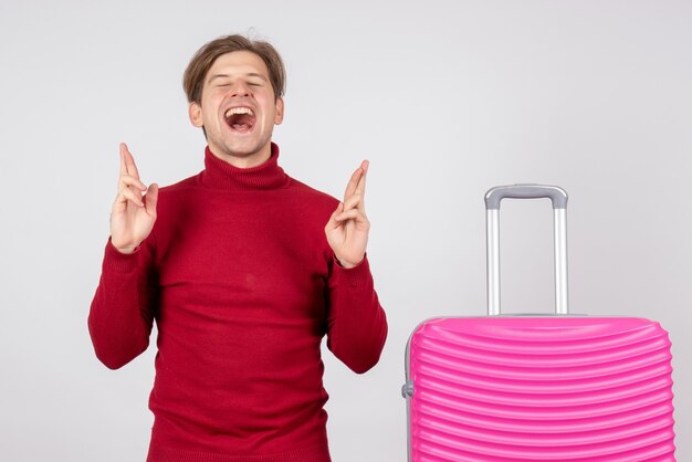 Front view of male tourist with pink bag on white wall