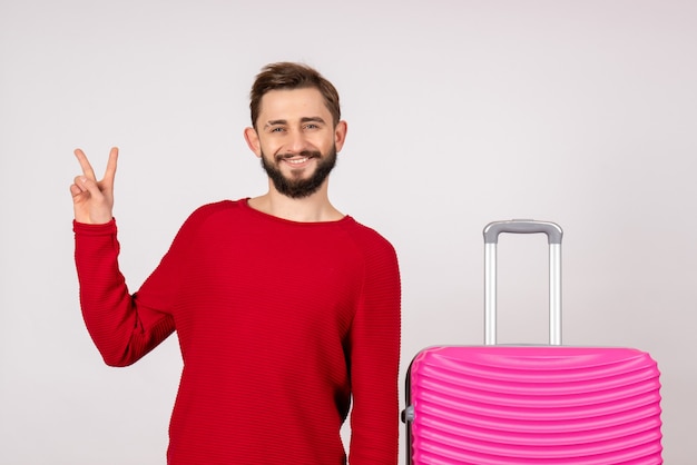 Front view male tourist with pink bag on a white wall