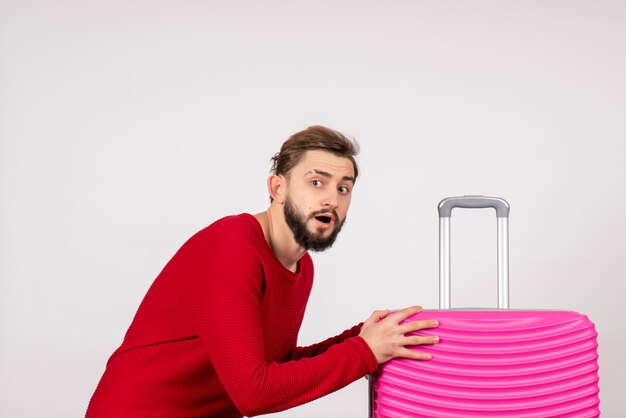 Front view male tourist with pink bag on white wall