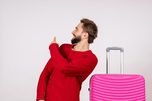 Front view male tourist with pink bag on white wall