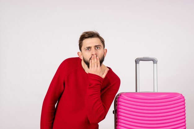 Front view male tourist with pink bag on white wall