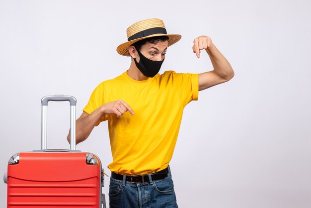 Front view male tourist with yellow t-shirt and red suitcase