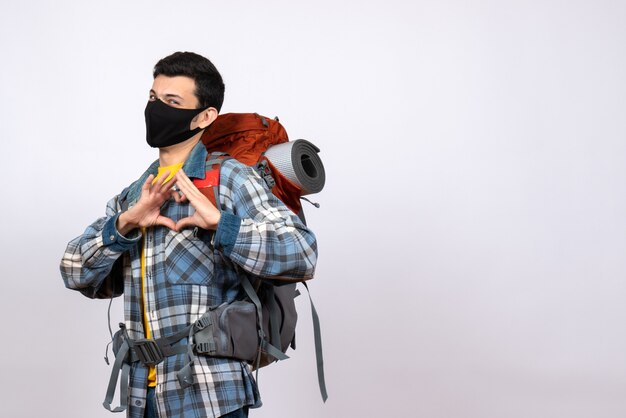 Front view male traveler with backpack and mask making heart sign