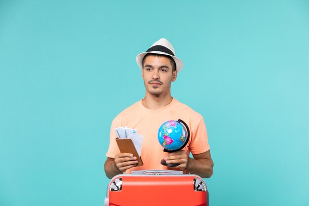 Front view male in vacation holding little globe and tickets on blue