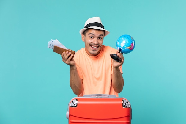 Front view male in vacation holding little globe and tickets on blue