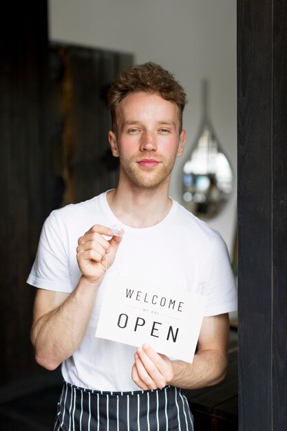 Front view of male waiter holding welcome sign