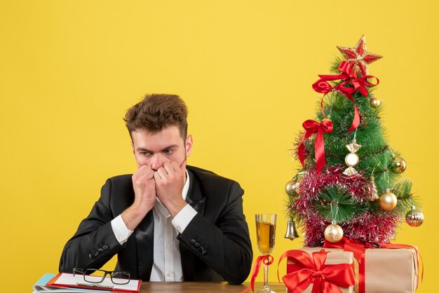 Front view male worker behind his working place with presents stressed on yellow 