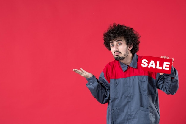 Foto gratuita vista frontale lavoratore maschio con targhetta rossa vendita su sfondo rosso meccanico foto casa colore shopping lavoro lavoratore uniforme strumento