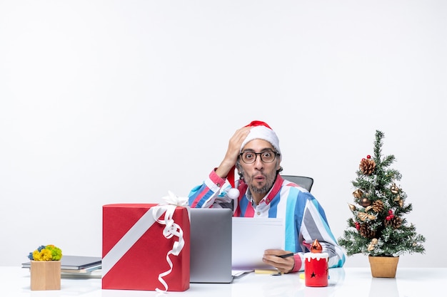 Front view male worker sitting in his place with laptop and files holding documents xmas office job emotion