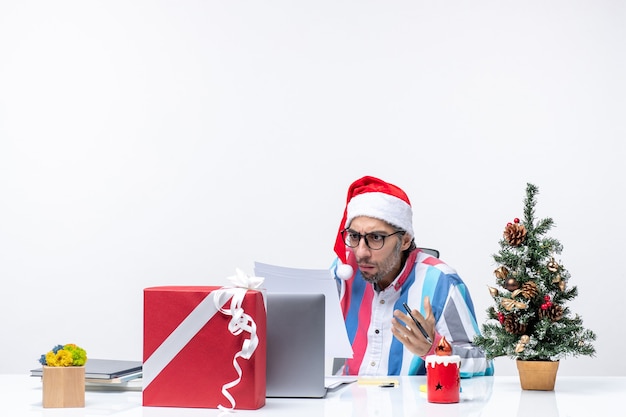 Вид спереди мужчина-работник, сидящий на своем месте с ноутбуком и файлами, работающий с документами, офисная эмоция, работа, рождество