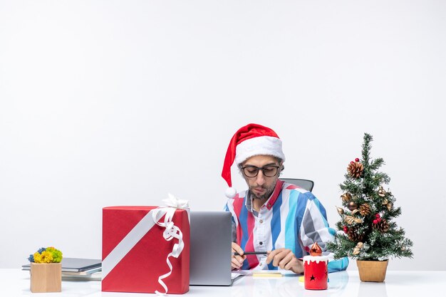 Front view male worker sitting in his place with laptop and files writing notes