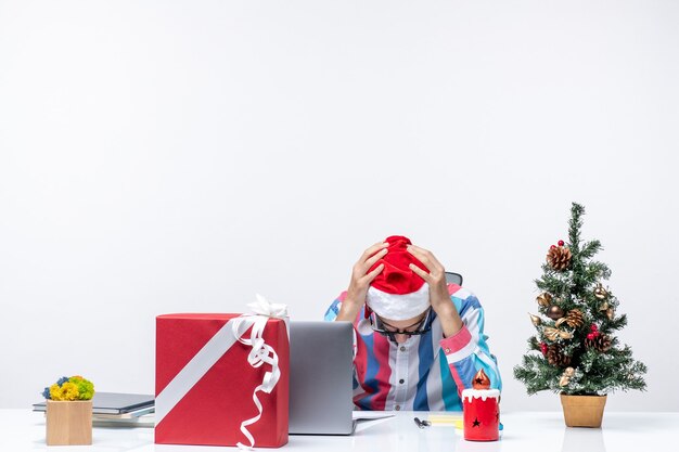 Вид спереди мужчина-работник, сидящий на своем месте с ноутбуком, устал от работы, эмоции, офис, рождество