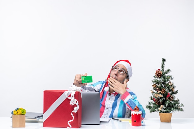 Front view male worker sitting in his working place holding green bank card holiday emotion christmas office job money