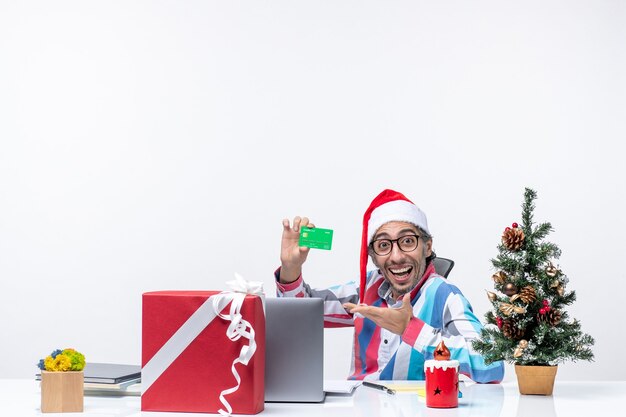 Front view male worker sitting in his working place holding green bank card job office christmas money emotion