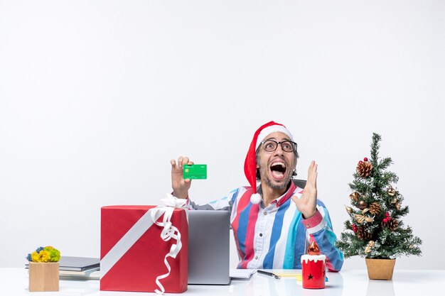 Front view male worker sitting in his working place holding green bank card job office christmas money emotions